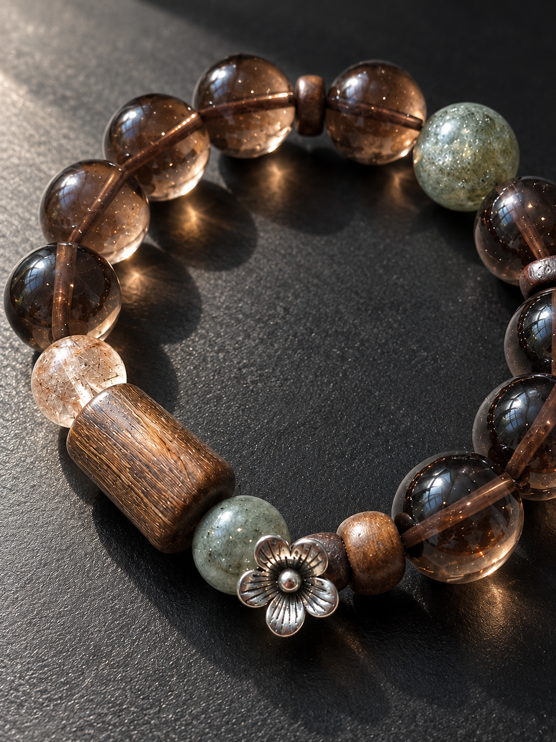 Close-up of Ice Obsidian, agarwood plaque, green crystal and Black Gold Super Seven bracelet beads
