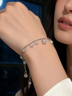 Woman's wrist wearing the blue and grey moonstone crystal bracelet resting on a windowsill at dusk