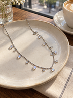 Natural Moonstone chain necklace with delicate dangling gemstone details displayed on a ceramic plate