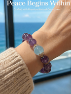 Hand wearing amethyst and aquamarine bracelet resting on an open book and laptop at a study desk